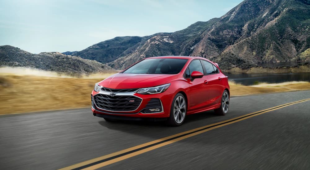 A red 2019 Chevy Cruze hatchback is driving in front of mountains.