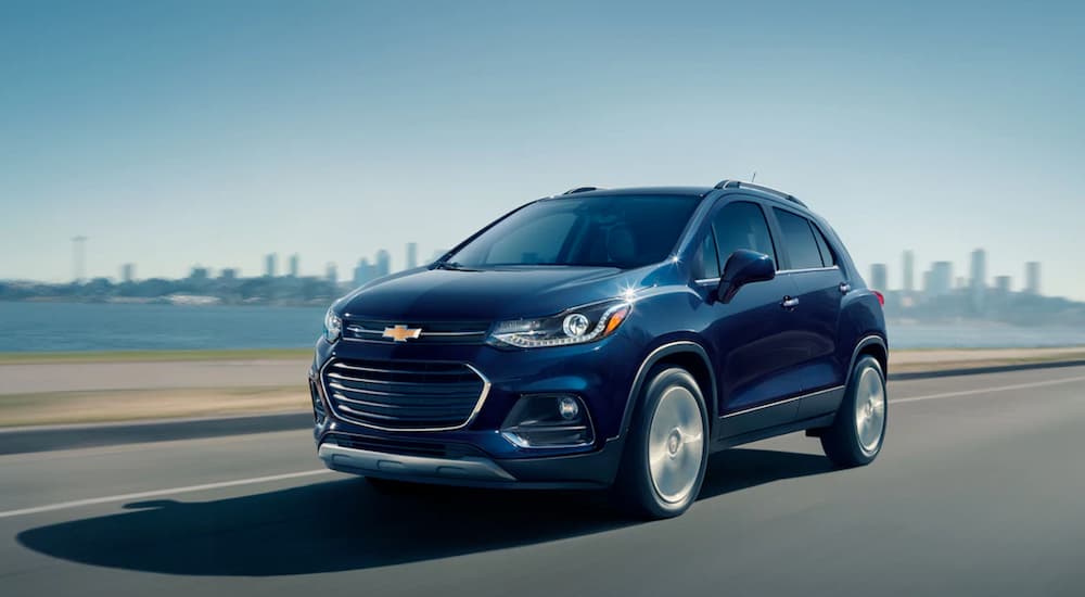A blue 2019 Chevy Trax is driving away from a city.