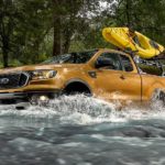 A gold 2019 Ford Ranger is crossing a river. Check out the solid comparison between the 2019 Ford Ranger vs 2020 Jeep Gladiator.