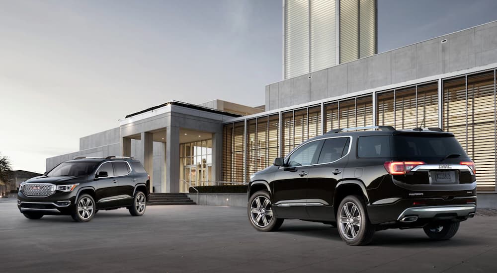 Two black GMC Acadias are parked at a dealership.