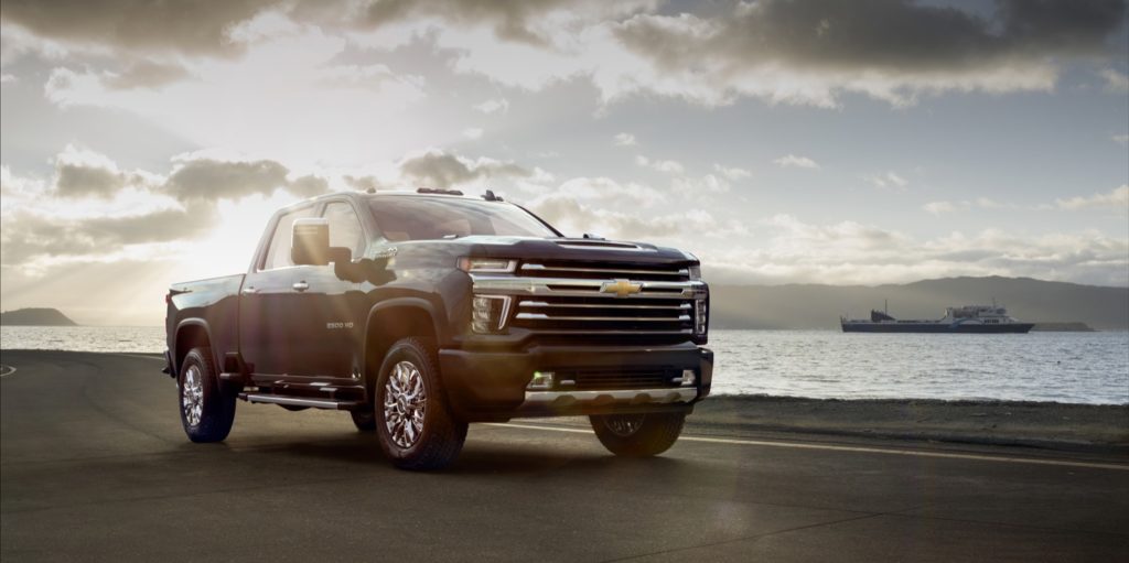 Black 2020 Chevy Silverado High Country in front of water with large boat in distance