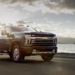 Black 2020 Chevy Silverado High Country in front of water with large boat in distance