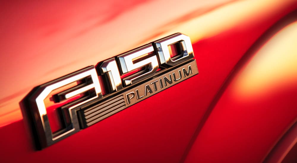 A closeup of a Ford F-150 Platinum emblem is shown on a red body panel.