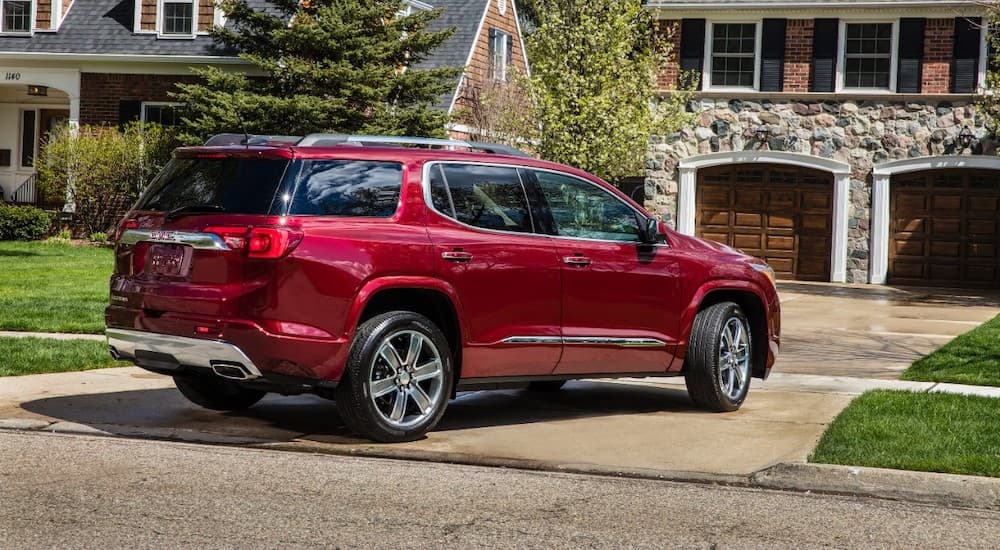 A red 2017 GMC Acadia Denali is pulling into a driveway.