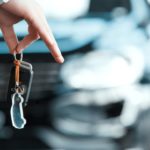 A closeup of someone holding keys to the used SUV for sale in the background is shown.
