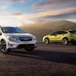 A silver and a green 2015 Subaru Crosstrek are parked in an open area.