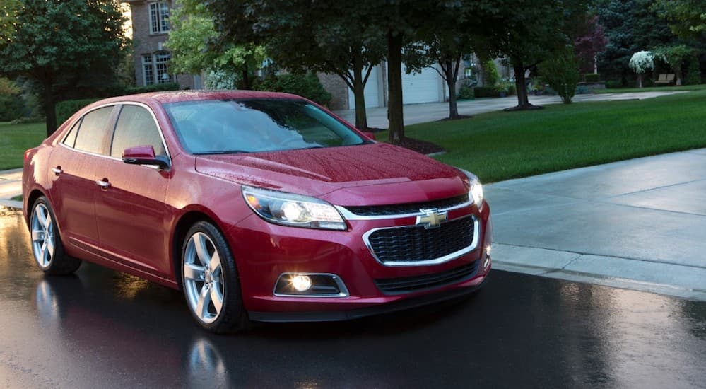 A 2015 Chevy Malibu, popular among used cars, is on a wet road at dusk.