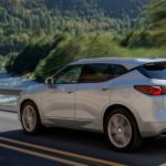 A silver 2019 Chevy Blazer is driving past a river lined with trees.