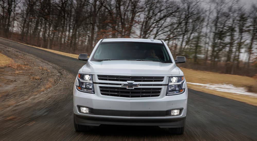 A white 2019 Chevy Tahoe is facing front while driving on a paved road.