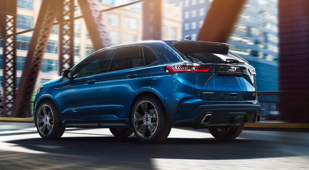 A blue 2019 Ford Edge is driving across a city bridge.