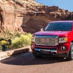 A red 2019 GMC Canyon Denali is in front of a desert canyon.