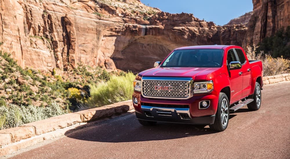 A red 2019 GMC Canyon Denali is in front of a desert canyon.