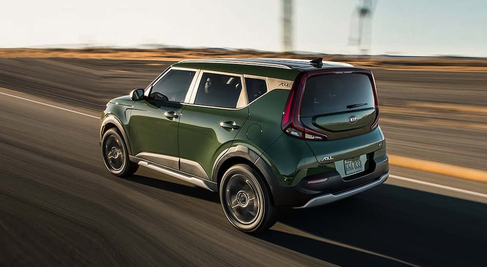 A green 2020 Kia Soul is driving past a desert.