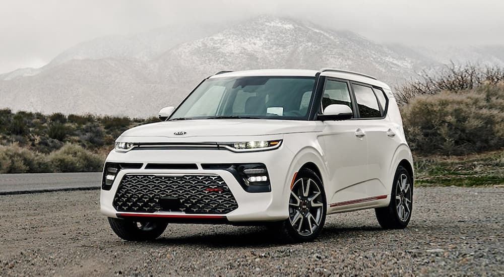 A white 2020 Kia Soul is parked in front of foggy mountains.