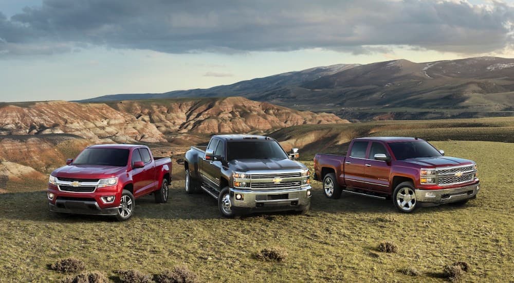 A 2015 Chevy Colorado, SilveradoHD, Silverado 1500 are in a field and all used Chevy truck options.