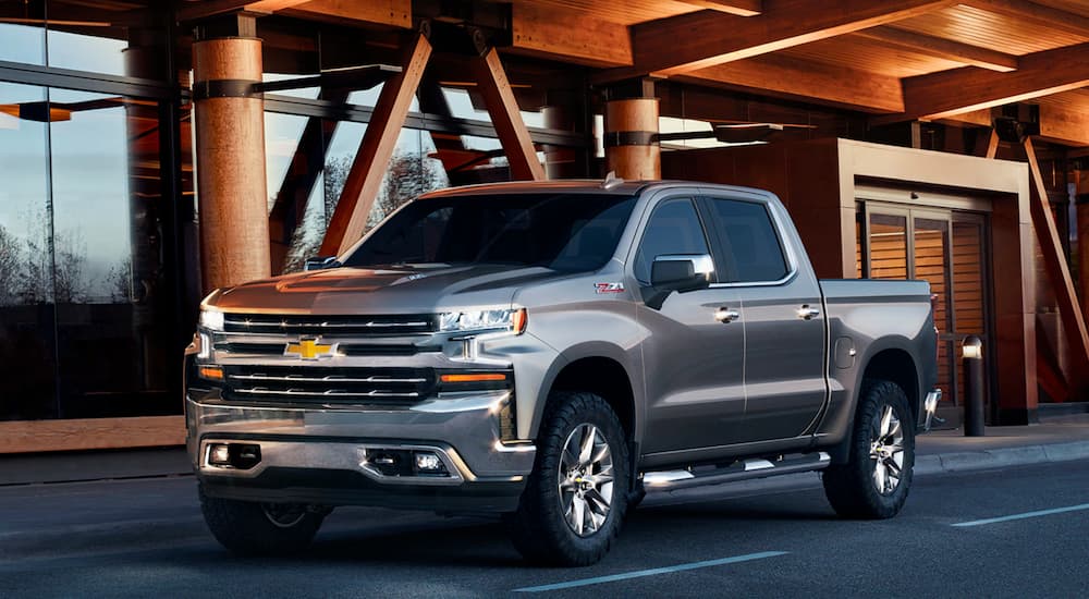 A grey 2020 Chevy Silverado is parked outside of a wood and glass building at a Chevy dealer.