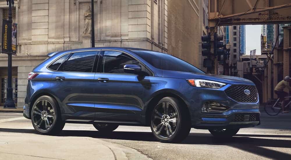 A blue 2020 Ford Edge, similar to ones that you'll find at your local car dealers, is driving on a city street.
