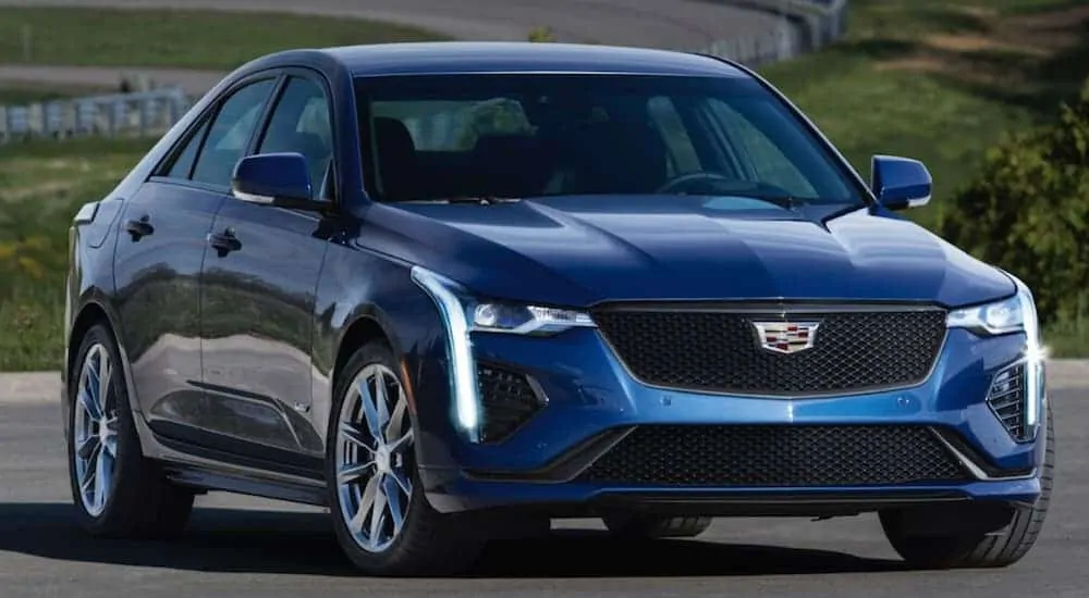 A blue 2020 Cadillac CT4 is parked on a winding road.