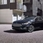 A black 2020 Ford Fusion is parked between two cement buildings.