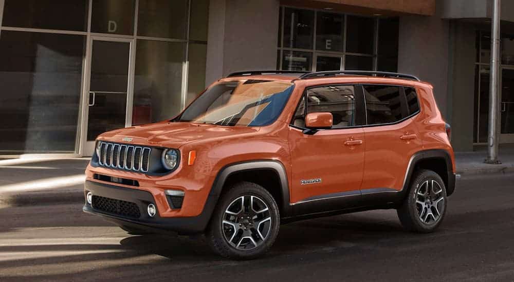 An orange 2020 Jeep Renegade is parked in front an office building.
