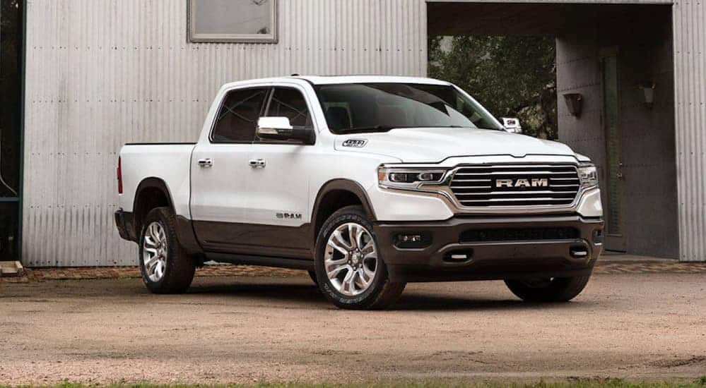A white 2020 Ram 1500 is parked in front of a metal walled building.