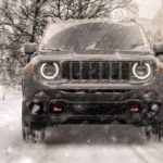 A grey 2020 Jeep Renegade is driving on a snow covered road during a snow storm.