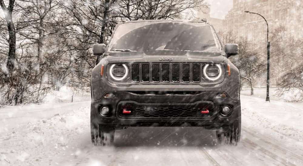 A grey 2020 Jeep Renegade is driving on a snow covered road during a snow storm.