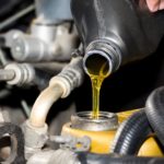 A close-up of oil being poured into a car engine during an oil change.