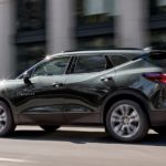 A green 2020 Chevy Blazer is driving on a city street.