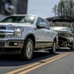 A white 2020 Ford F-150, which wins when comparing the 2020 Ford F-150 vs 2020 Ram 1500 is towing a boat.