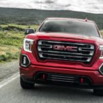 A red 2020 GMC Sierra 1500, which wins when comparing the 2020 GMC Sierra 1500 vs 2020 Nissan Titan, is driving with hills in the distance.