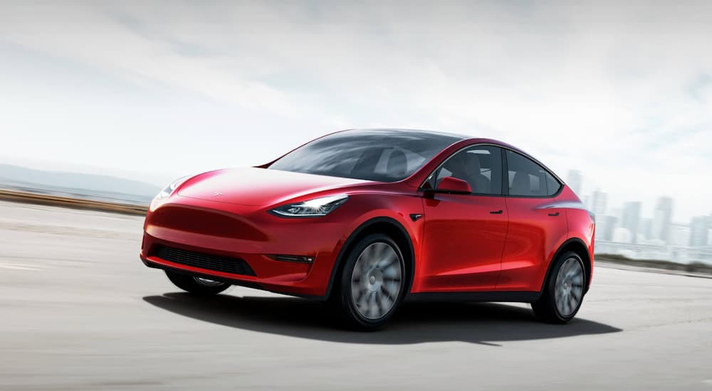 A red Tesla Model Y is driving on a highway.