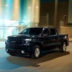 A black 2020 Chevy Silverado 1500 is driving through a city at night after leaving a Chevy dealer near me.