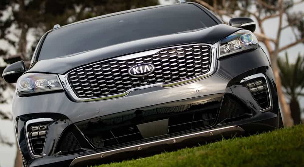 A close up of a grey Kia SUV's front grille is shown.