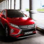 A red 2020 Mitsubishi Eclipse Cross is driving on a covered road with large pillars to the side.