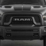 A close up of the black front grille on a Ram truck that says 'RAM' on it.