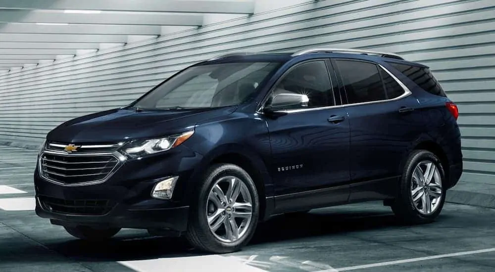 A blue 2020 Chevy Equinox is parked in a dark garage.