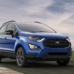 A blue 2020 Ford Ecosport, which wins when comparing the 2020 Ford EcoSport vs 2020 Chevy Trax, is driving on an empty highway.