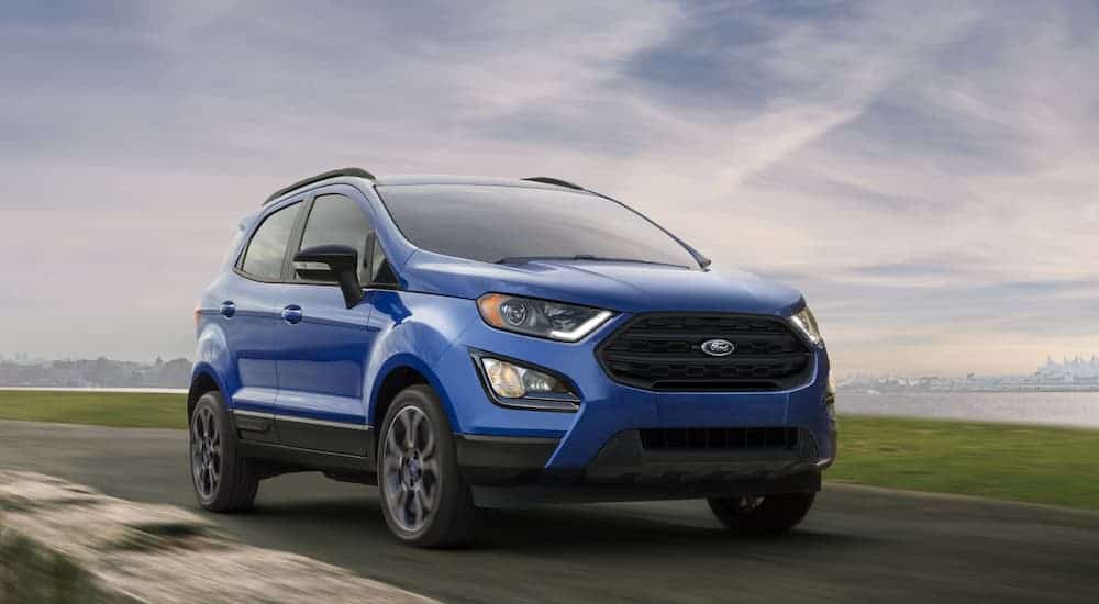 A blue 2020 Ford Ecosport, which wins when comparing the 2020 Ford EcoSport vs 2020 Chevy Trax, is driving on an empty highway.