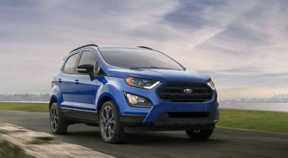 A blue 2020 Ford Ecosport, which wins when comparing the 2020 Ford EcoSport vs 2020 Chevy Trax, is driving on an empty highway.