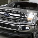 A silver 2020 Ford F-150 is driving under a bridge.