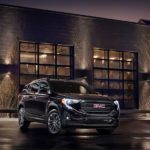 A black 2020 GMC Terrain is parked in front of an industrial building at night after leaving a GMC dealer.