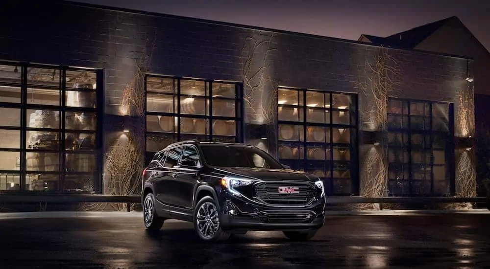 A black 2020 GMC Terrain is parked in front of an industrial building at night after leaving a GMC dealer.