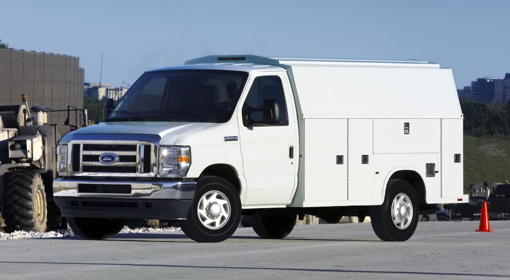 A White 2021 Ford E-Series with a utility upfit is at a construction site.