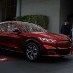 A red 2021 Ford Mustang Mach-E is parked on a red carpet while in front of a restaurant at night.