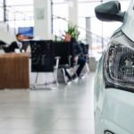 A close up of a white car is shown while parked in a car dealership's showroom.