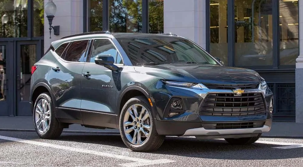 A dark green 2020 Chevy Blazer, a popular model at Chevy dealerships near me, is parked in front of a street side restaurant.