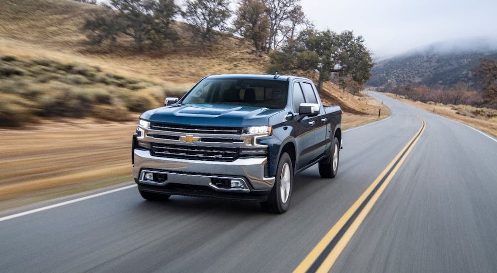 A blue 2020 Chevy Silverado 1500 diesel is driving on an empty highway.