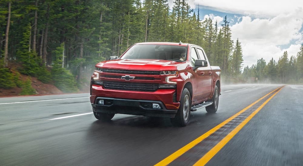 A popular Chevy diesel truck for sale near you, a red 2020 Chevy Silverado 1500 diesel, is driving on a misty forest highway.