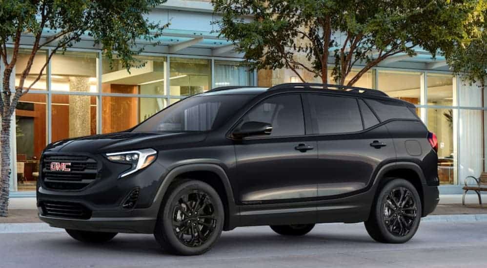 A black 2020 GMC Terrain, which wins when comparing the 2020 GMC Terrain vs 2020 Ford Escape, is parked in front of an office building.
